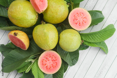 Flat lay of red guava fruit Psidium Guajava decorated with guava leaves. Slices of ripe and fresh red guava
