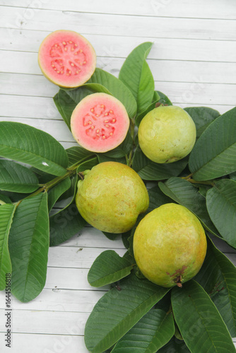 Flat lay of red guava fruit Psidium Guajava decorated with guava leaves. Slices of ripe and fresh red guava