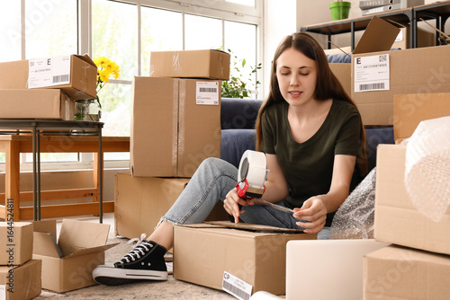 Young woman taping parcel f...