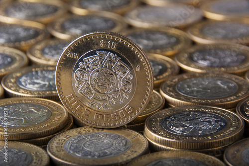 Monedas mexicanas apiladas en el fondo y al frente una moneda de 10 pesos

Mexican coins stacked in the background and a 10 peso coin in front