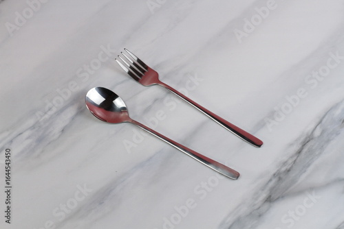 Metal spoons and forks on a marble table. Asian tableware.