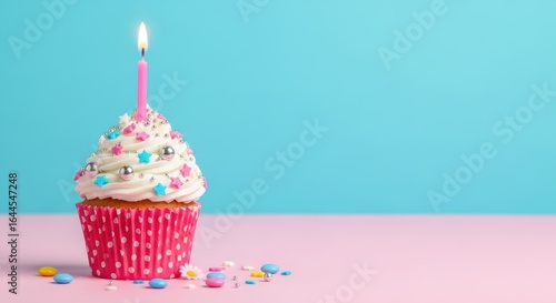 Birthday Cupcake with Lit Pink Candle and Sprinkles on Pink and Blue Background