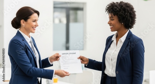 Wallpaper Mural Two women in business attire, one holding a document labeled 'OFFER LETENT' in an office setting. Torontodigital.ca