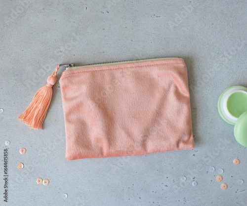 Peach velour zipper makeup bag with tassel, lip balm in a round green jar and pink sequins on gray