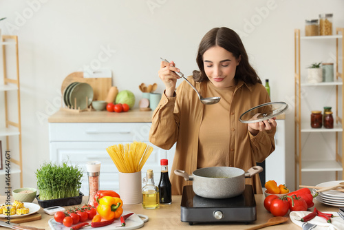 Young woman tasting soup in...