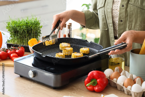 Young woman frying corn on ...