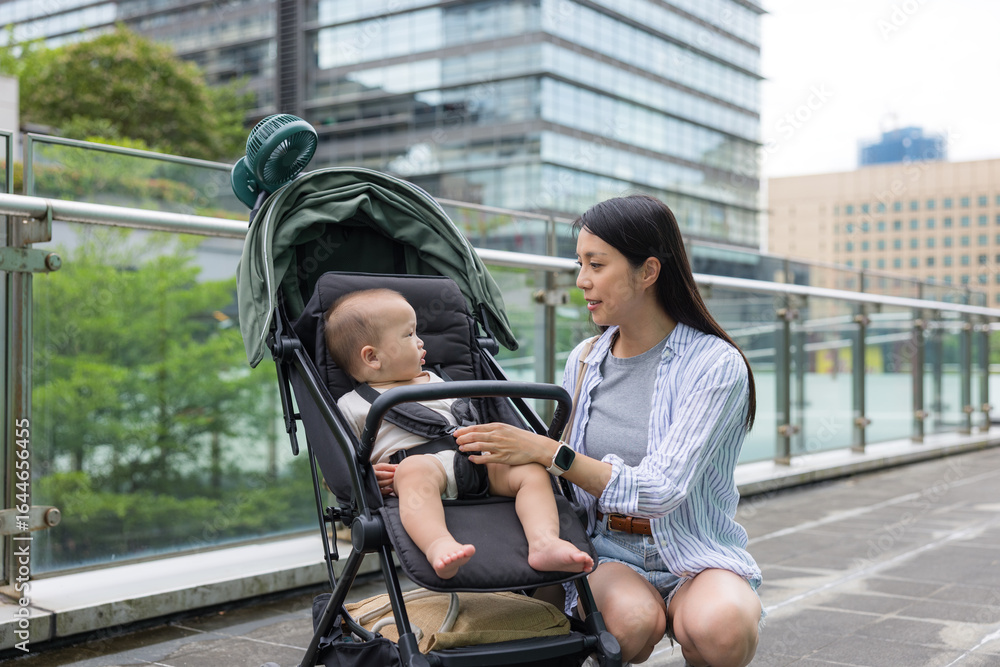 Obraz premium Mother look at her baby son on stroller in city