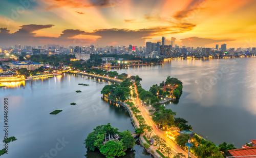 Fototapeta Naklejka Na Ścianę i Meble -  Aerial view of road crossing the island Westlake, Hanoi, Vietnam with green tree lined street, temple located between small oasis. A beautiful sunset in capital of Vietnam