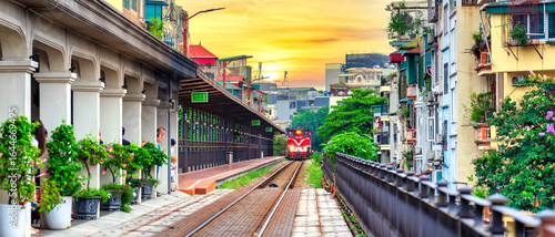 Train running on ancient railway at Long Bien bridge station in Hanoi, Vietnam with market community