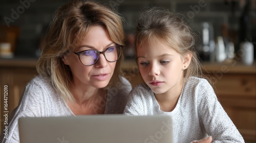 A caring mother and her inquisitive young daughter enjoying quality family time together exploring educational content on a sleek portable computer in a bright cozy living room setting.