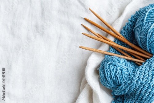 Light blue yarn, knitting needles on white cloth