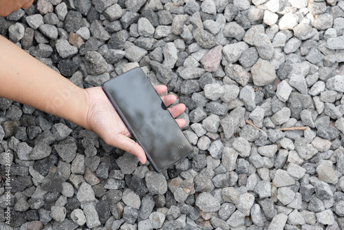 A person is holding a cell phone in their hand. The phone is black and has a case