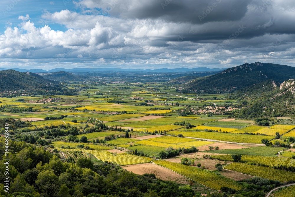 Fototapeta premium Panoramic view of a valley. Rolling hills, vibrant fields, and distant mountains. Partly cloudy sky