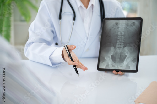 Orthopedist doctor explain spine lumber vertebrae x-ray image on digital tablet to the patient for diagnose Herniated Disc disease and Spondylosis, Spondylolisthesis.