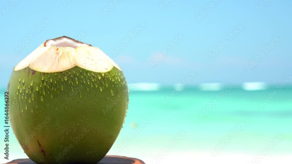 Fresh coconut on a wooden table with a stunning beach and turquoise waters in the background Fresh coconut on a wooden table with a stunning beach and turquoise waters in the background
