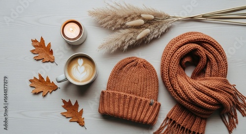 Fototapeta Naklejka Na Ścianę i Meble -  Aesthetic autumn flat lay with cappuccino, candle, beanie, scarf, pampas grass and leaves on white wooden background for cozy fall season vibes