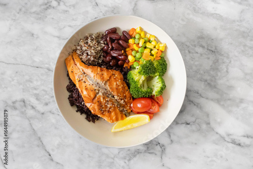 Grilled salmon grain bowl with vegetables and lemon
