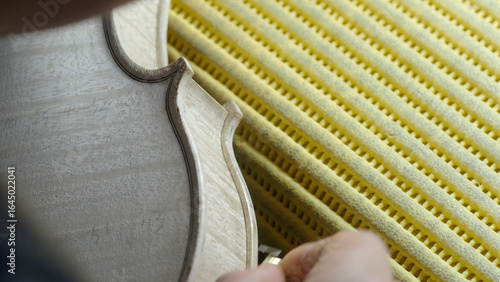 Obraz na plátně Skilled craftsman carefully sanding wooden violin body, highlighting intricate w