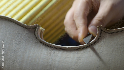 Fotografie Experienced luthier carefully carving intricate f hole on wooden violin surface,