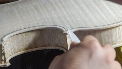 Obraz na plátně Skilled luthier hand carving violin edge with professional chisel, revealing int