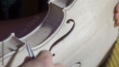 Fotografie Skilled craftsman carefully shaping wooden violin body, using specialized gouge