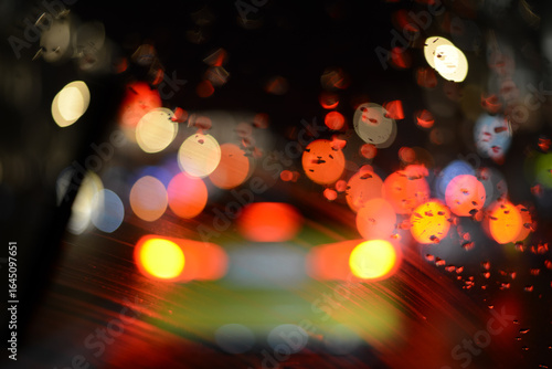 Blurred lights of the night city pass through the windshield of the car just wiped by the wipers, but with scum along the edge where the brush did not wipe. High quality photo