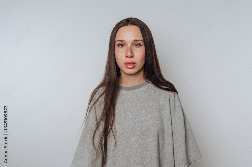 Fototapeta premium portrait of young woman shows a serious expression with striking eyes on light background