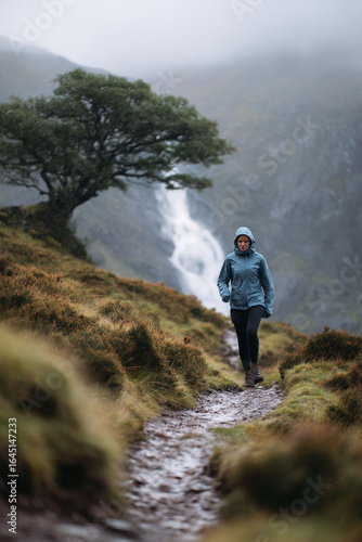 A woman hiking through a misty, rainy mountain landscape. Solitude and perseverance embodied. Ideal for travel, wellness, or outdoor adventure themes.