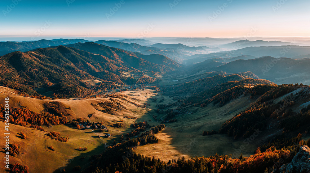 Fototapeta premium Expansive panorama of golden hills and misty mountain ridges under morning light. A majestic and peaceful autumn landscape with forested slopes and natural texture.
