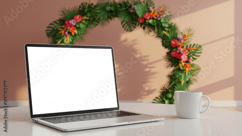 Stylish home office workspace with a laptop mockup featuring a blank white screen on a desk. A coffee mug and lush tropical floral arch create a relaxed scene.