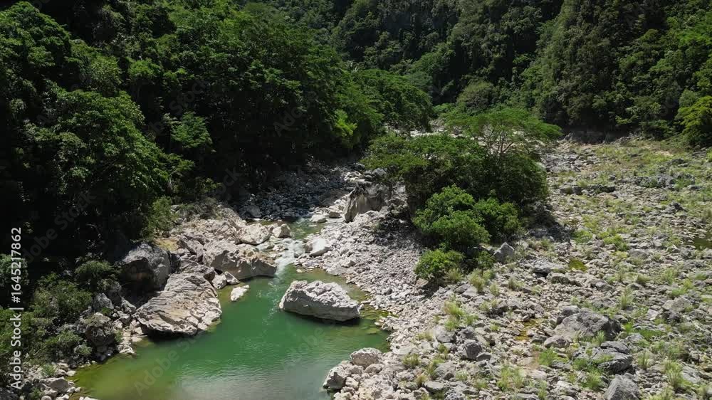 Shot from below rising upward showing river, rocks with plants, then shifting to top view of lush green mountains around Tinipak River, Philippines. Shot from below rising upward showing river, rocks with plants, then shifting to top view of lush green mountains around Tinipak River, Philippines.