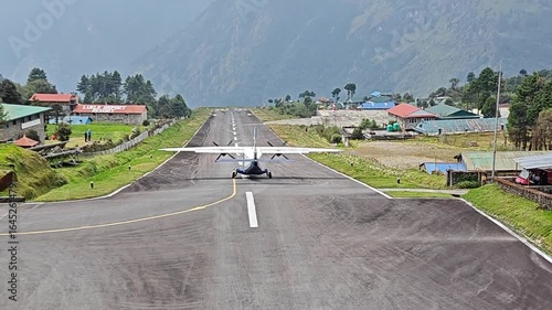Lukla, Nepal - May 08, 2025: Lukla airport. Small airplane ascends from picturesque runway surrounded by mountains and village