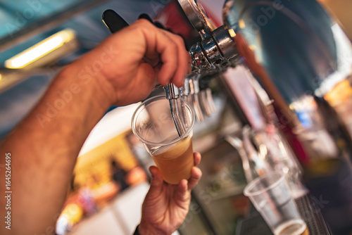 Bartender pouring craft beer into plastic cup at festival