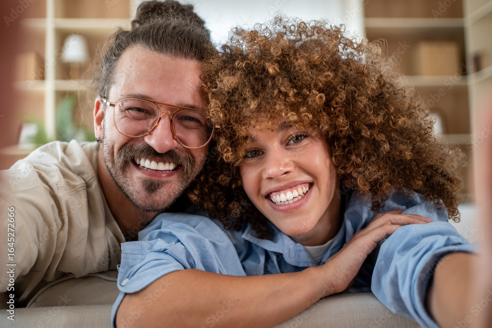 Fototapeta premium Happy couple taking selfie on sofa at home
