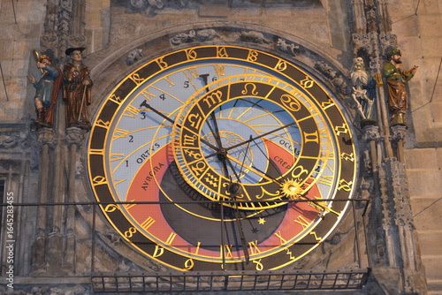 a close-up of the Prague Astronomical Clock, showcasing its intricate and golden astrolabe. This historical timepiece features multiple dials with astronomical and zodiac symbols. 