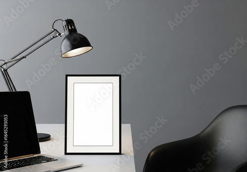 Modern Desk Setup with Laptop, Lamp, and Blank Frame