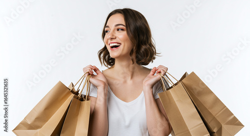 A smiling woman holding several brown paper shopping bags against a white studio background