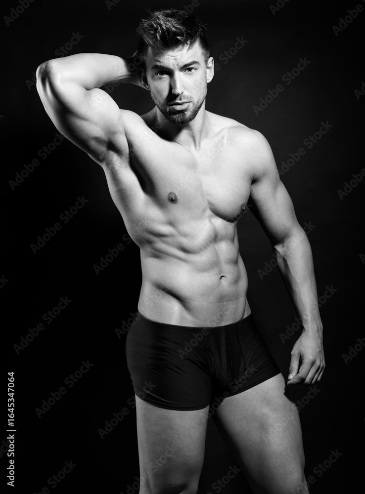 Fototapeta premium Handsome young muscular bodybuilding man posing in underwear with visible six pack in black and white