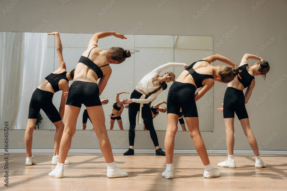 Obraz premium Rear view. Trainer is teaching girls ballet dancing