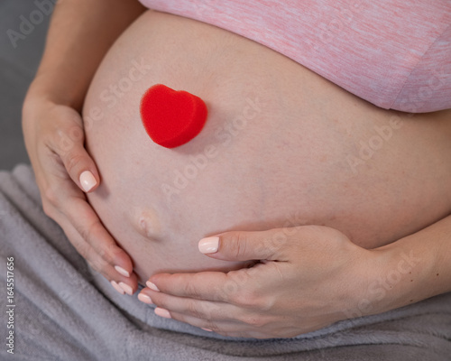 Wallpaper Mural Caucasian pregnant woman holding heart on belly background. Third trimester.  Torontodigital.ca