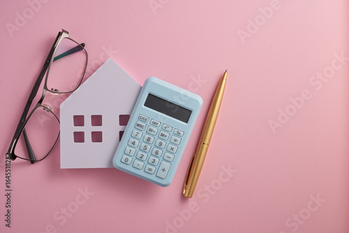 House model, pen ,eyeglasses and calculator on pink background