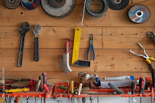 A wooden wall in the garage with tools and other accessories. Screwdrivers, wire cutters, and sanding discs. All the trappings of a man in the garage