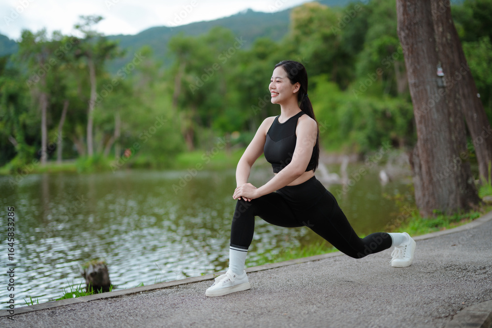 Young sportswoman stretching legs by the lake in a park Young sportswoman stretching legs by the lake in a park