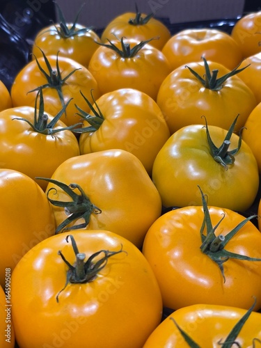 yellow tomatoes big on the counter in the store background
