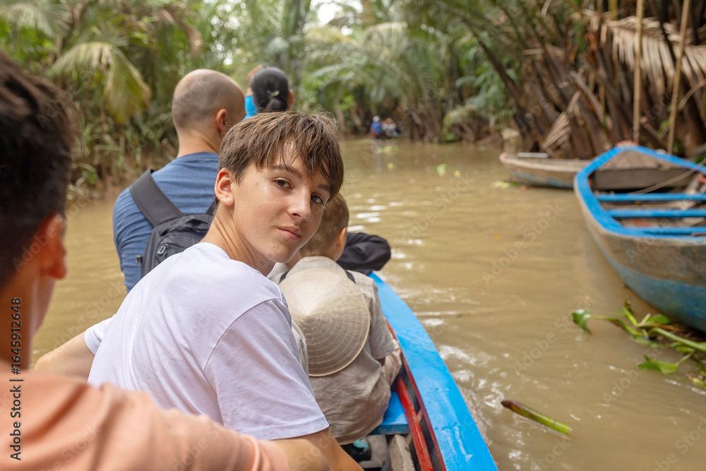 Fototapeta premium Happy european family, visiting Mekong river in Vietnam on a summer day, boat trip and local habits