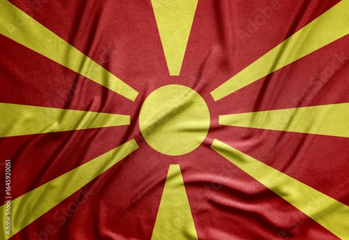 red and yellow flag of the European country North Macedonia on a rough canvas with folds and shadows