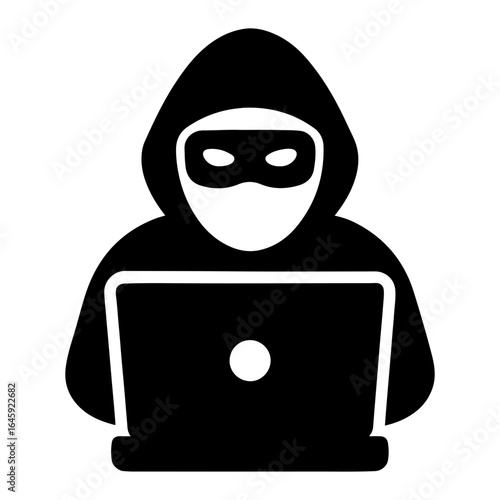 A hooded hacker is working on a laptop to steal data and break into a secure system to commit cyber crime