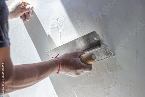 Hands of a construction worker applying plaster on wall