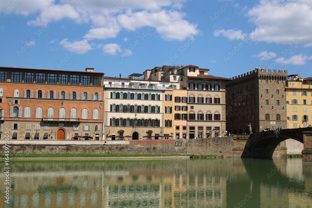 Obraz premium Houses buildings on the banks of river Arno. Buildings with reflections in the water, Firenze, Tuscany, Italy.