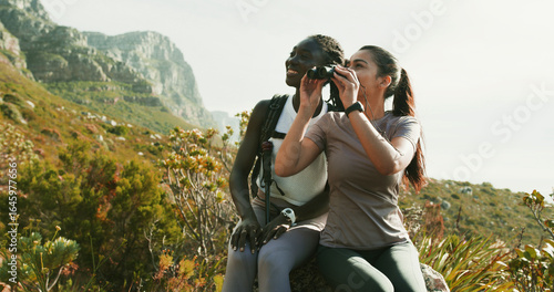 Women, friends and relax with binocular for hiking, nature sightseeing and mountain view. Happy, people and gear for travel, backpacking adventure and birdwatching observation with wildlife search